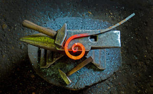 Blacksmithing project under way with glowing curled metal on anvil