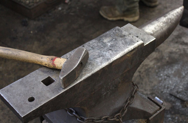 A blacksmith's hammer resting on an anvil in the smithy at summer camp