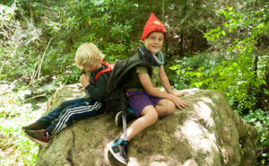 Boys at Asheville nature connection camp climbing a boulder in the forest