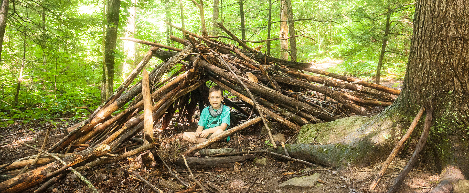 Deep in the forest a boy at summer day camp enjoys his primitive hut