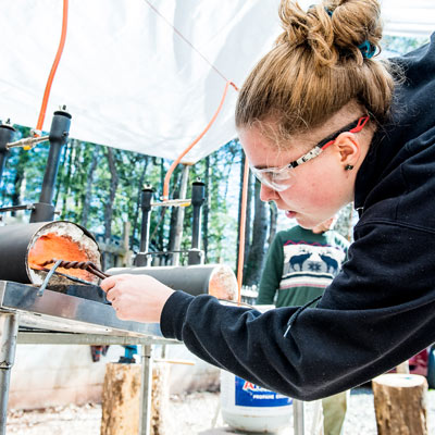 Young woman learning blacksmithing at Asheville day camp
