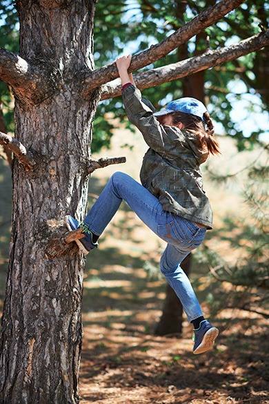 Homeschool student climbing tree in forest parkour course