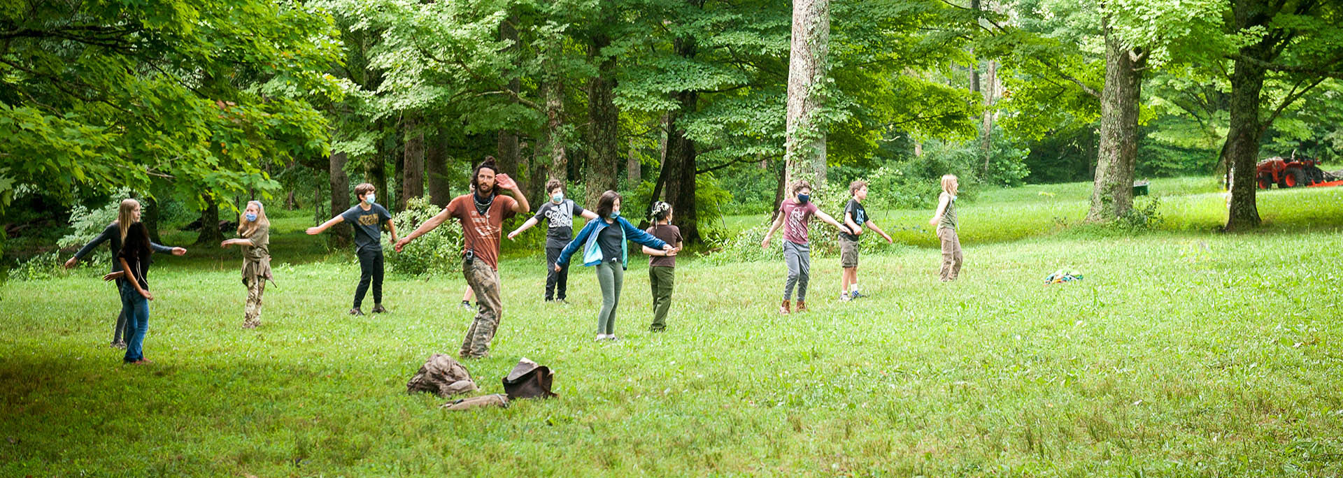 Group of nature connection campers in field by forest edge learning martial arts based movement class