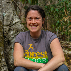 Photo of Kerensa Bartlett the nature connection mentor seated on a log in the forest