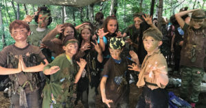 Kids goofing around in group photo for Forest Ninjas camp striking funny poses in natural camouflage