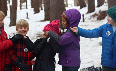Diverse group of children playing in snow at Asheville homeschool nature connection program