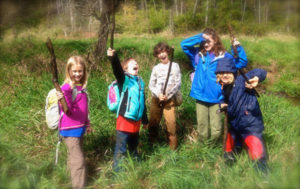 Summer campers pose with their throwing sticks at survival skills camp near Asheville