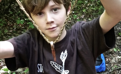 Boy holding pendant and necklace made at nature camp