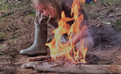 Child learning to make fire at Asheville day camp for learning survival skills