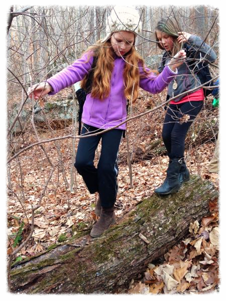 Young girls practicing stealth and balance walking on a log at forest school